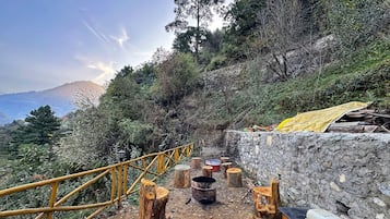 Sit on the bench amidst the serene mountain landscape, surrounded by a bamboo fence and natural surroundings.