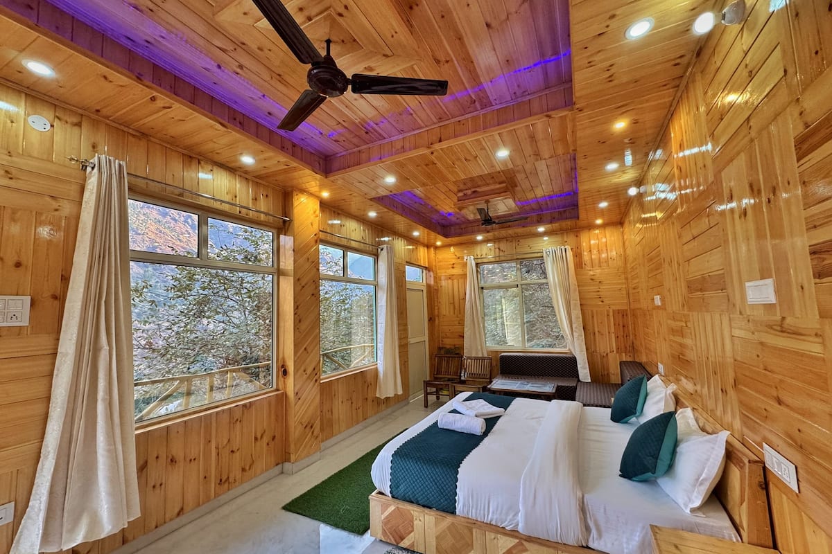 A wooden cabin bedroom with a bed, a desk, and a chair.