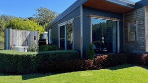 Ein modernes Haus mit großen Glasfenstern, einer Holzterrasse und einem gepflegten Rasen.