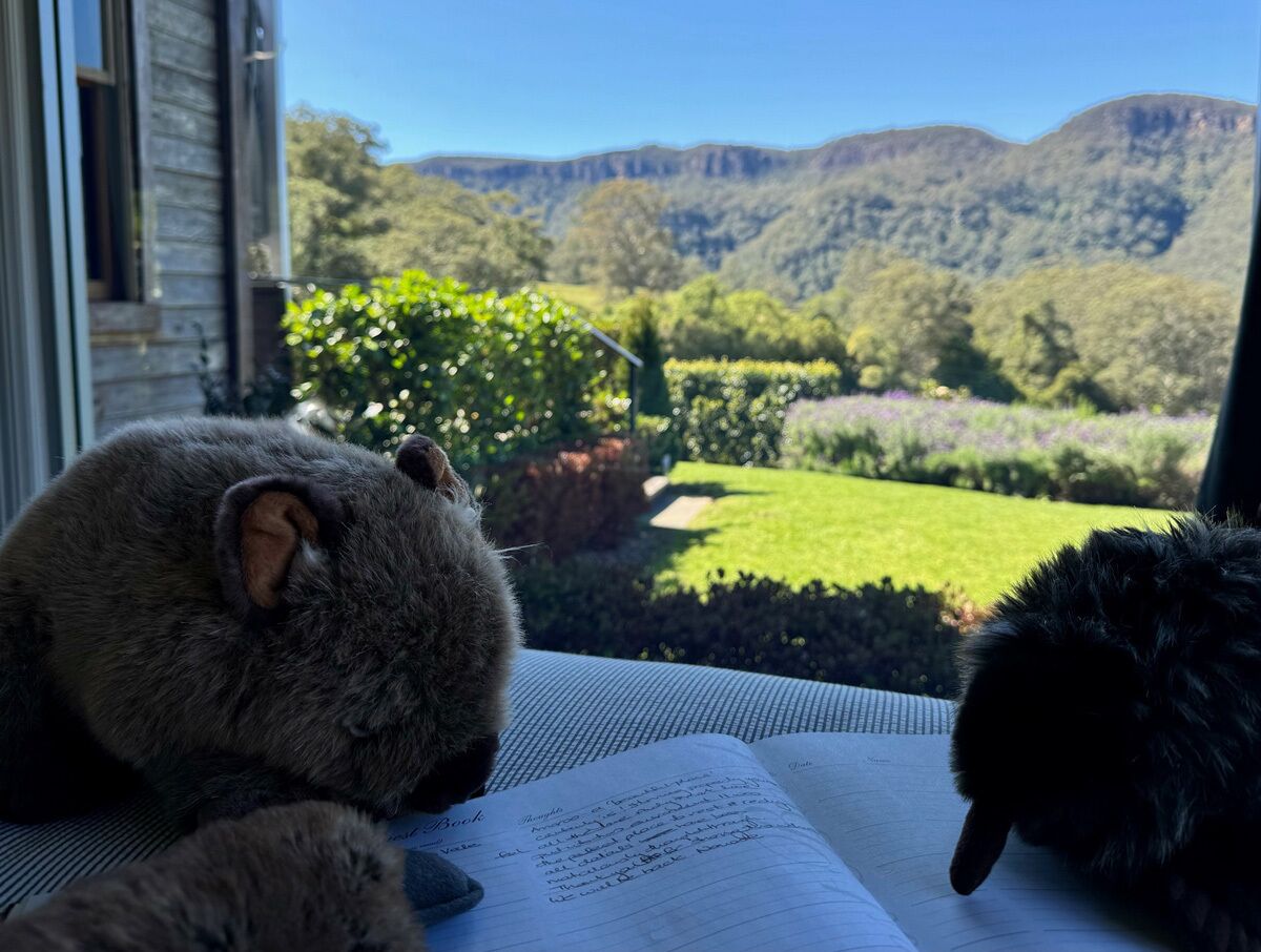 Una habitación con vista a un paisaje montañoso, una ventana y un libro sobre una mesa.