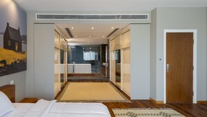 Une chambre d’hôtel avec un grand lit, une salle de bain avec baignoire et un couloir menant à une autre pièce.