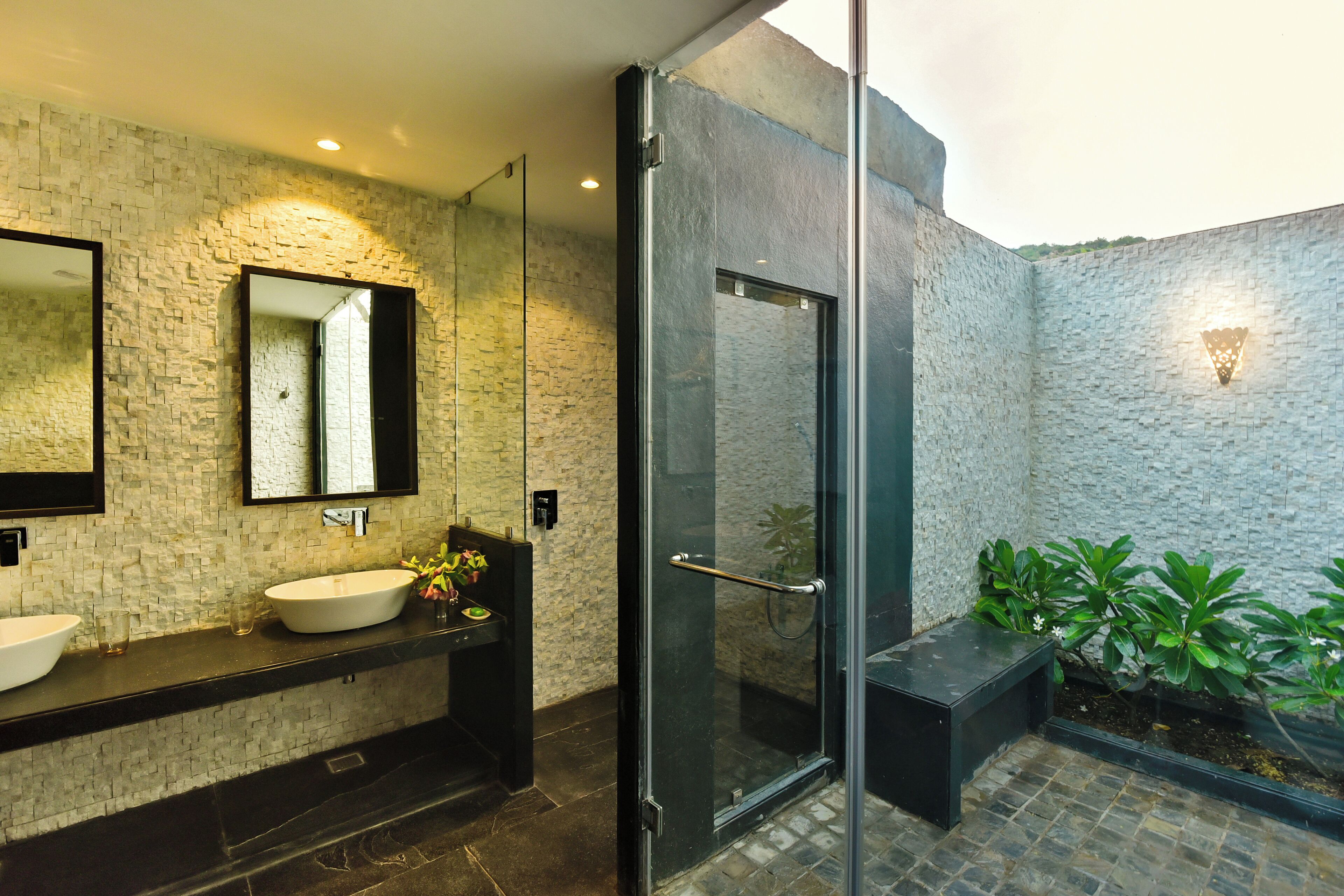 Ein modernes Badezimmer mit Steinwand, Duschkabine aus Glas und Waschbecken mit Spiegel.