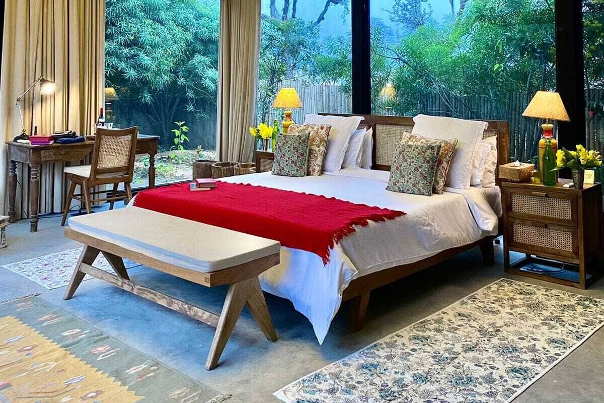 Une chambre dotée d’un grand lit, d’un bureau et d’une chaise, et offrant une vue sur la verdure environnante.