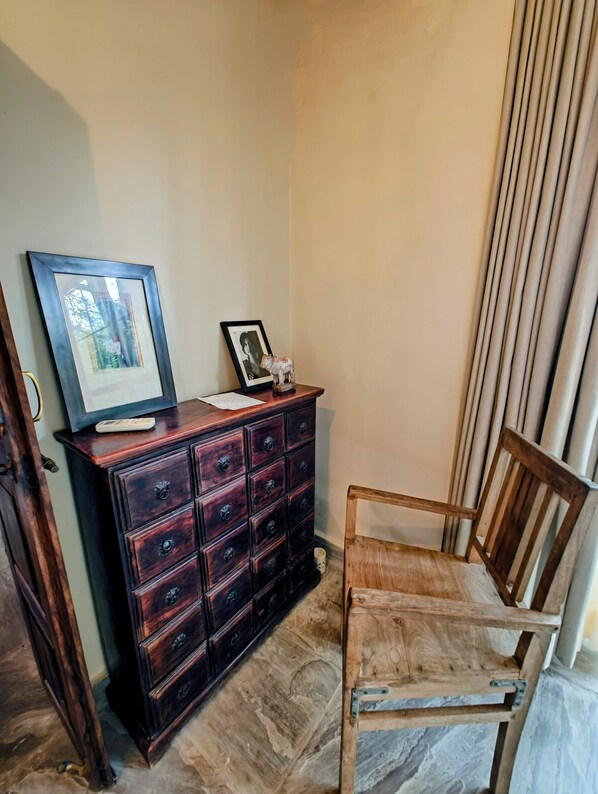 A corner room with a wooden cabinet, a chair, and a framed picture on the wall.