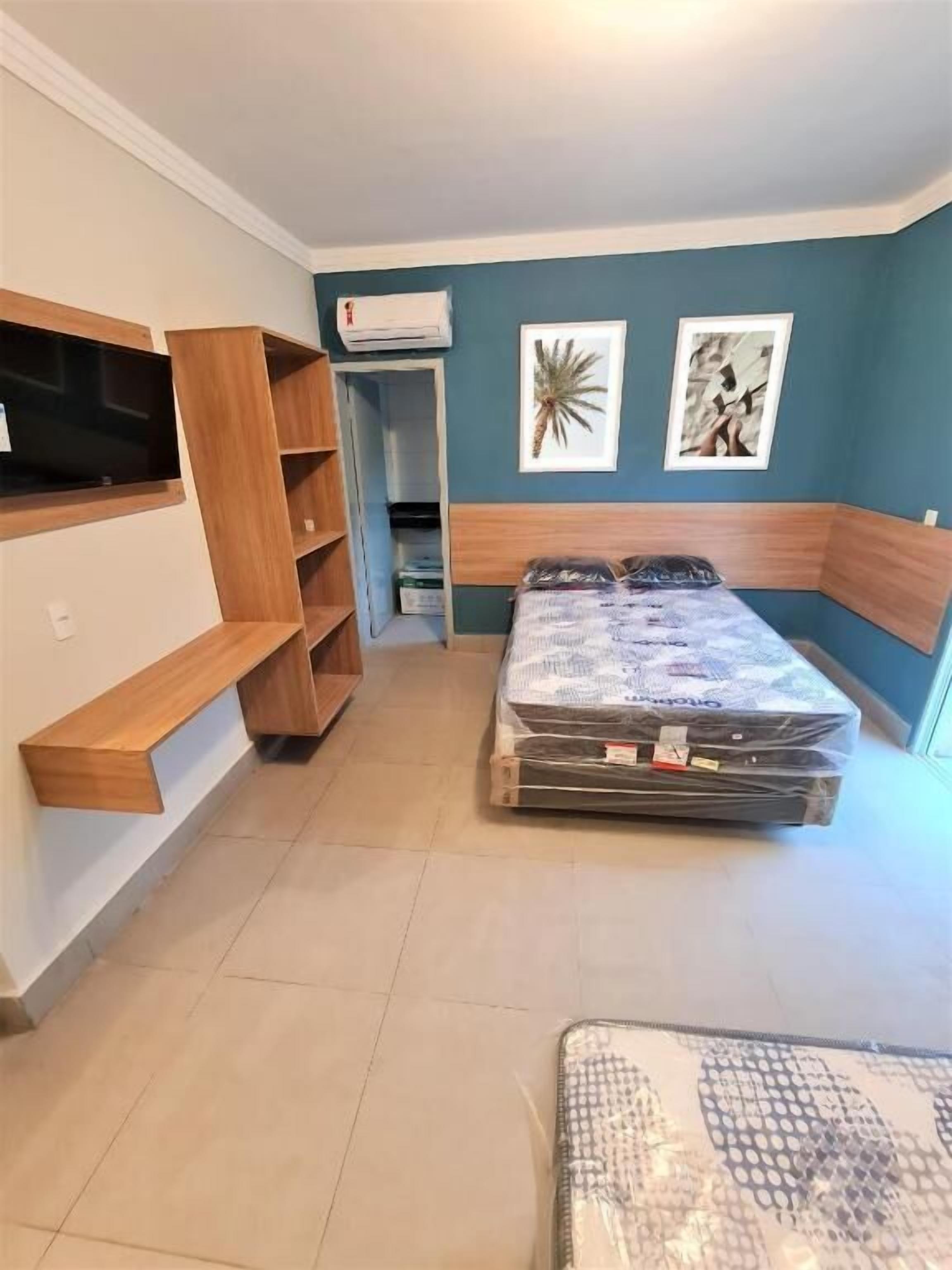 A compact bedroom with a bed, built-in shelving, and a small seating area.