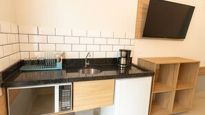 A compact kitchen with a built-in dishwasher, a coffee maker, and a sink. - Marmeu Enseada (Guarujá)