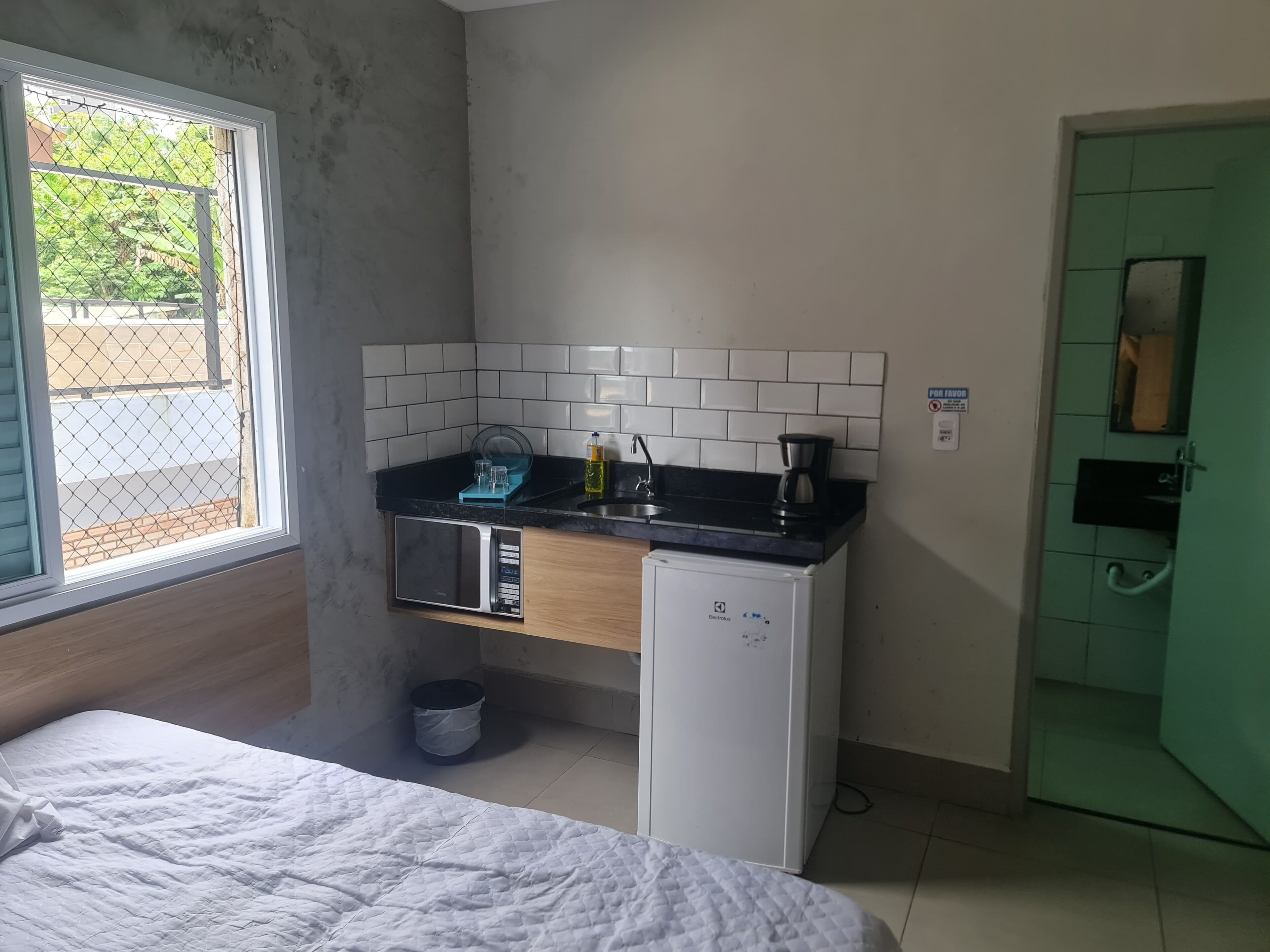 A compact kitchenette with a microwave, coffee maker, and sink.
