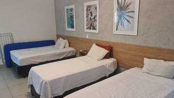 Une chambre d’hôtel avec deux lits simples, un canapé bleu et trois tableaux encadrés accrochés au mur.