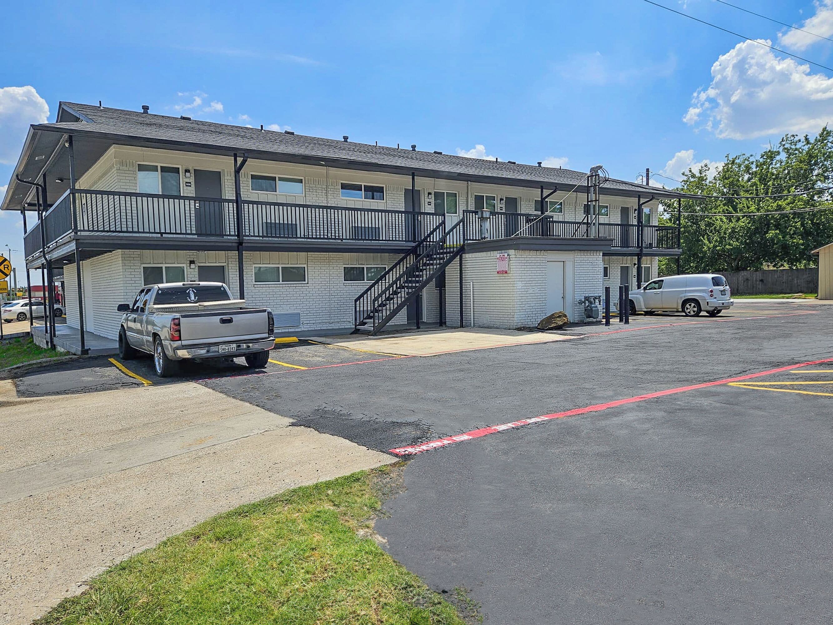 A motel with a two-story structure, a covered parking area, and a stairway to the upper level.