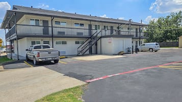 Un motel composé d’un bâtiment à deux étages, d’un espace de stationnement couvert et d’un escalier menant à l’étage supérieur.