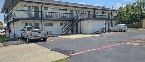 Un motel con una estructura de dos pisos, un área de estacionamiento techada y una escalera al nivel superior.