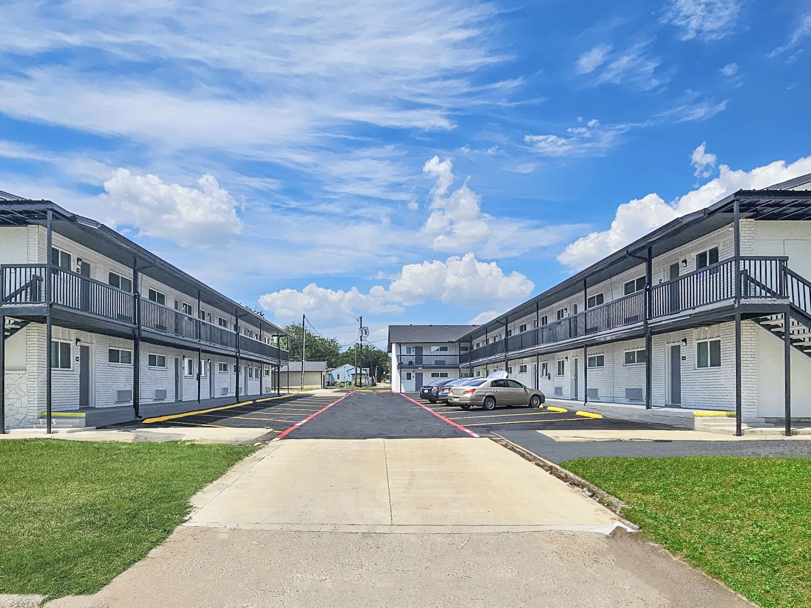 A row of two-story motel buildings with a central walkway and parking area.