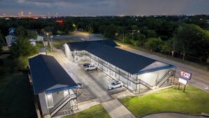 Een groot, industrieel gebouw met een plat dak, meerdere parkeerplaatsen en een trap naar een overdekt gebied.