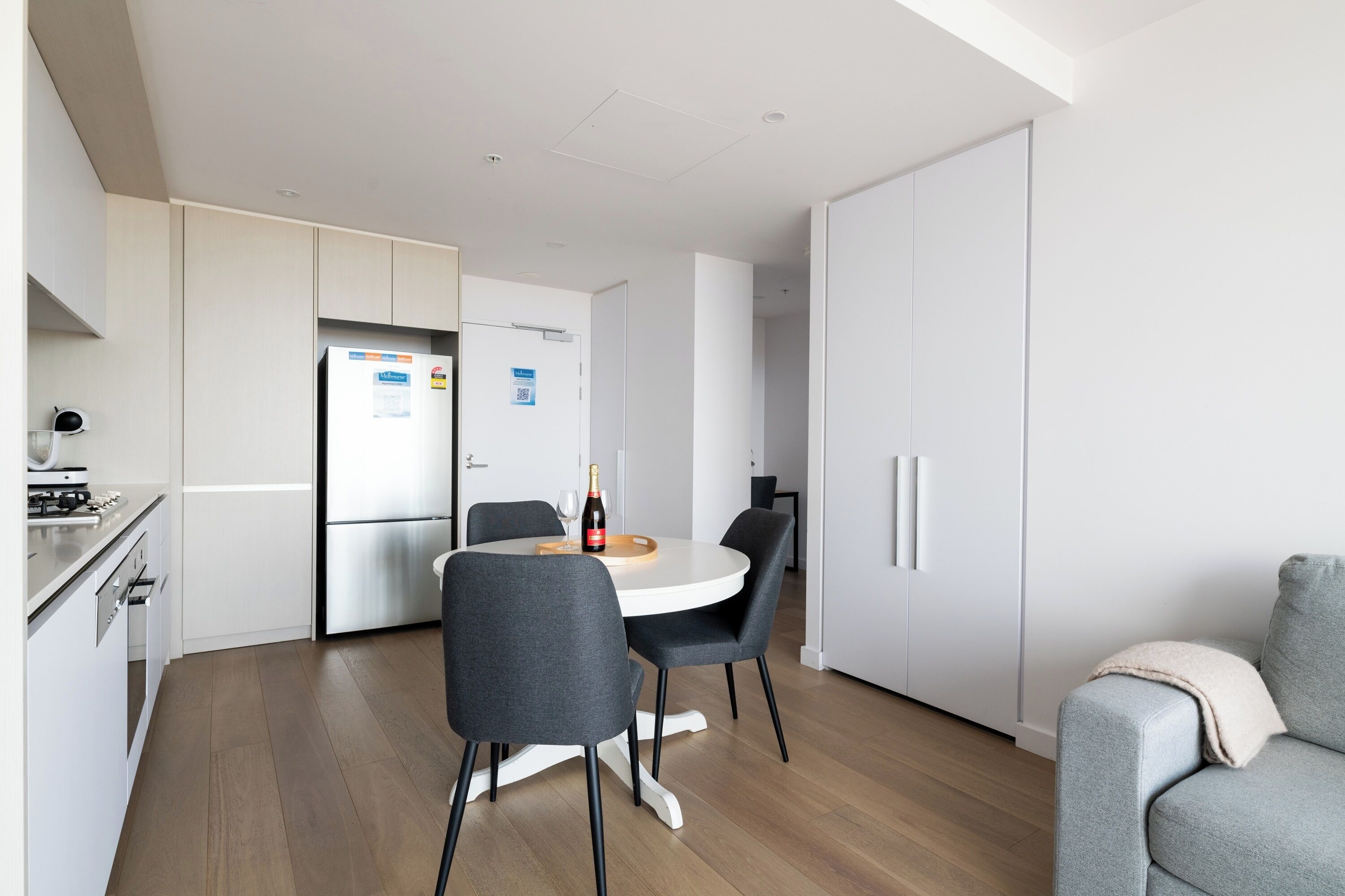 A modern kitchen with a dining table, chairs, and a refrigerator.