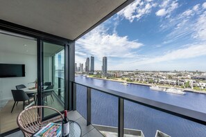 Ein moderner Balkon mit Blick auf die Stadt, eine Essecke mit Stühlen und ein Tisch mit Flasche und Zeitschrift.