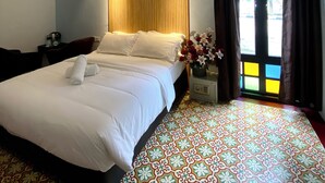 A hotel room with a bed, a ceiling fan, a nightstand with a lamp, and a window with curtains. - Bayu Bayu Hotel by Soft Loft (George Town)