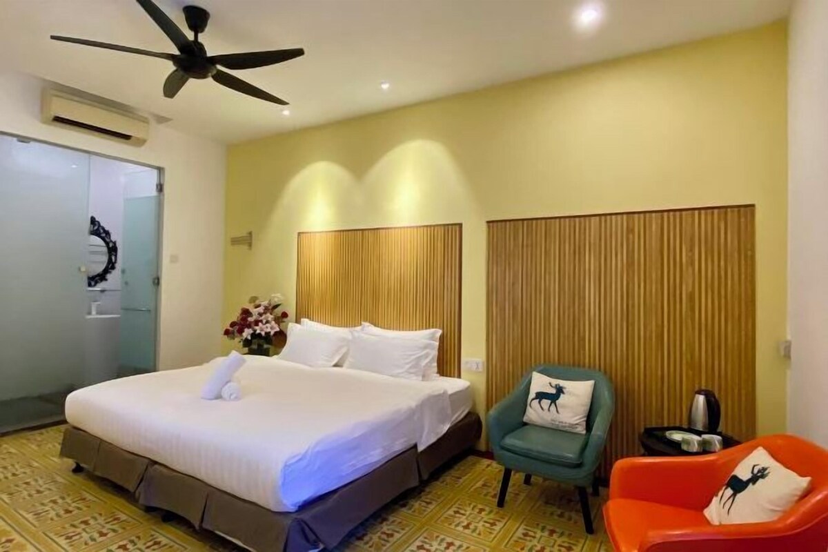 A hotel room with a large bed, two bedside tables, a ceiling fan, and a wall-mounted air conditioner.