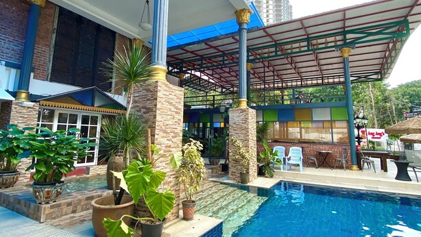 A pool area with a covered seating area, potted plants, and a view of a building with large windows. - Bayu Bayu Hotel by Soft Loft (George Town)