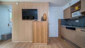 Una cocina moderna con armarios de madera, microondas integrado y televisor de pantalla plana montado en la pared.
