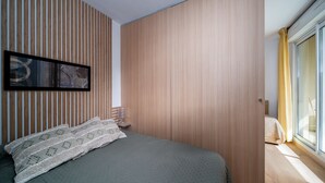 Un dormitorio moderno con cama, una obra de arte enmarcada en la pared y una ventana con cortinas.