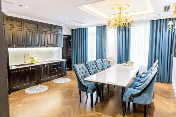 Una cocina moderna con armarios oscuros, una encimera blanca y una mesa de comedor grande con sillas tapizadas en azul.