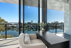 Een moderne kamer met een groot raam met uitzicht op een jachthaven en stadsgezicht.