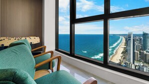 A room with a large window offering a view of the ocean and a beach.
