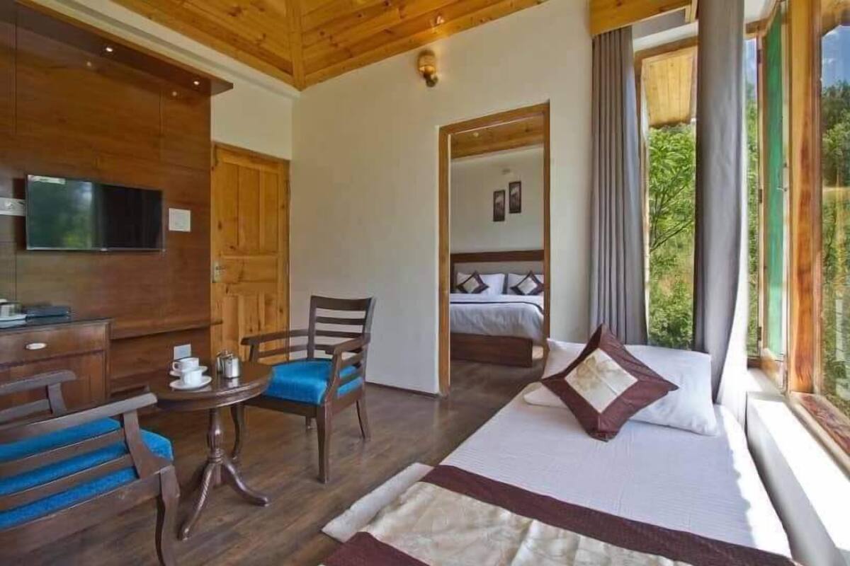 Una habitación acogedora con cama, sillón, una mesita y televisor.
