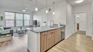 A modern kitchen with a central island, pendant lighting, and a ceiling fan. - Big Flat + 2 min to UM + 95 Walkscore (Missoula)