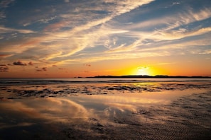 Dramatic golden sunset reflected on Rhosneigr beach, watched from the first floor living room of Swn Y Bae, pet-friendly holiday home, Anglesey