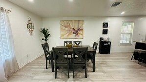 Un comedor con mesa y sillas, un cuadro en la pared y una planta.