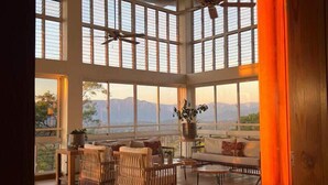 Una habitación amplia con techos altos, ventanas grandes y vistas a montañas.