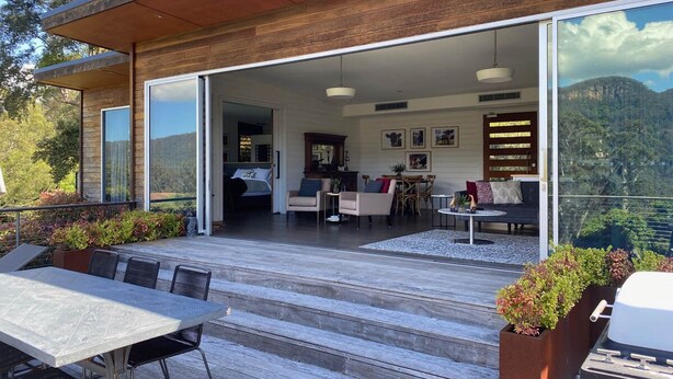 Une terrasse extérieure moderne dotée d’un espace repas, de sièges et offrant une vue sur les montagnes.
