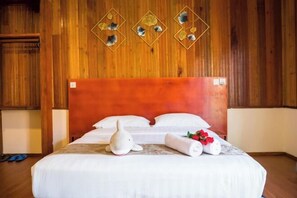 Une chambre d’hôtel avec une tête de lit en bois, un lit recouvert de draps blancs et un élément décoratif mural au-dessus du lit.