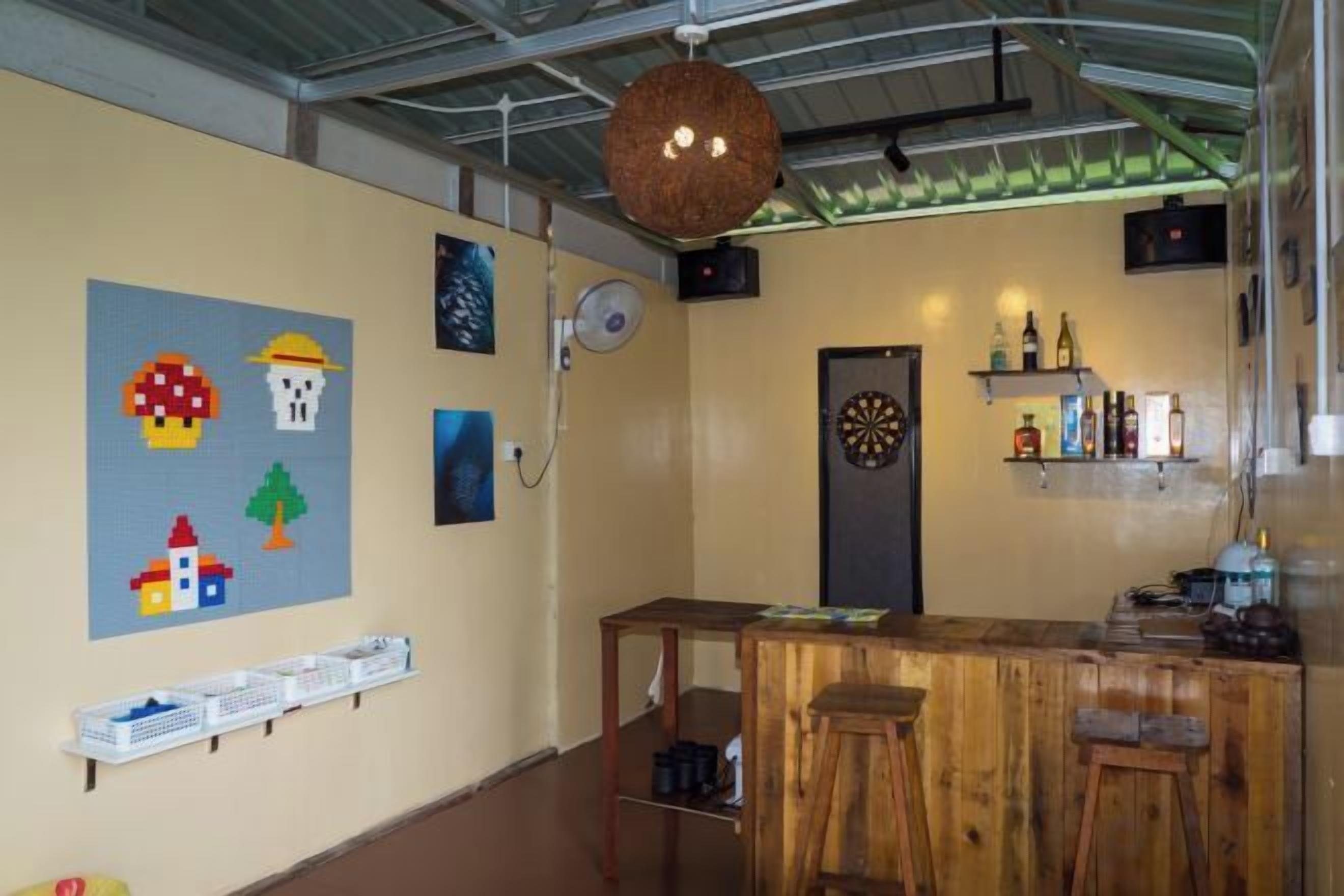A bar area with a dartboard, shelves with bottles, and a wooden counter.