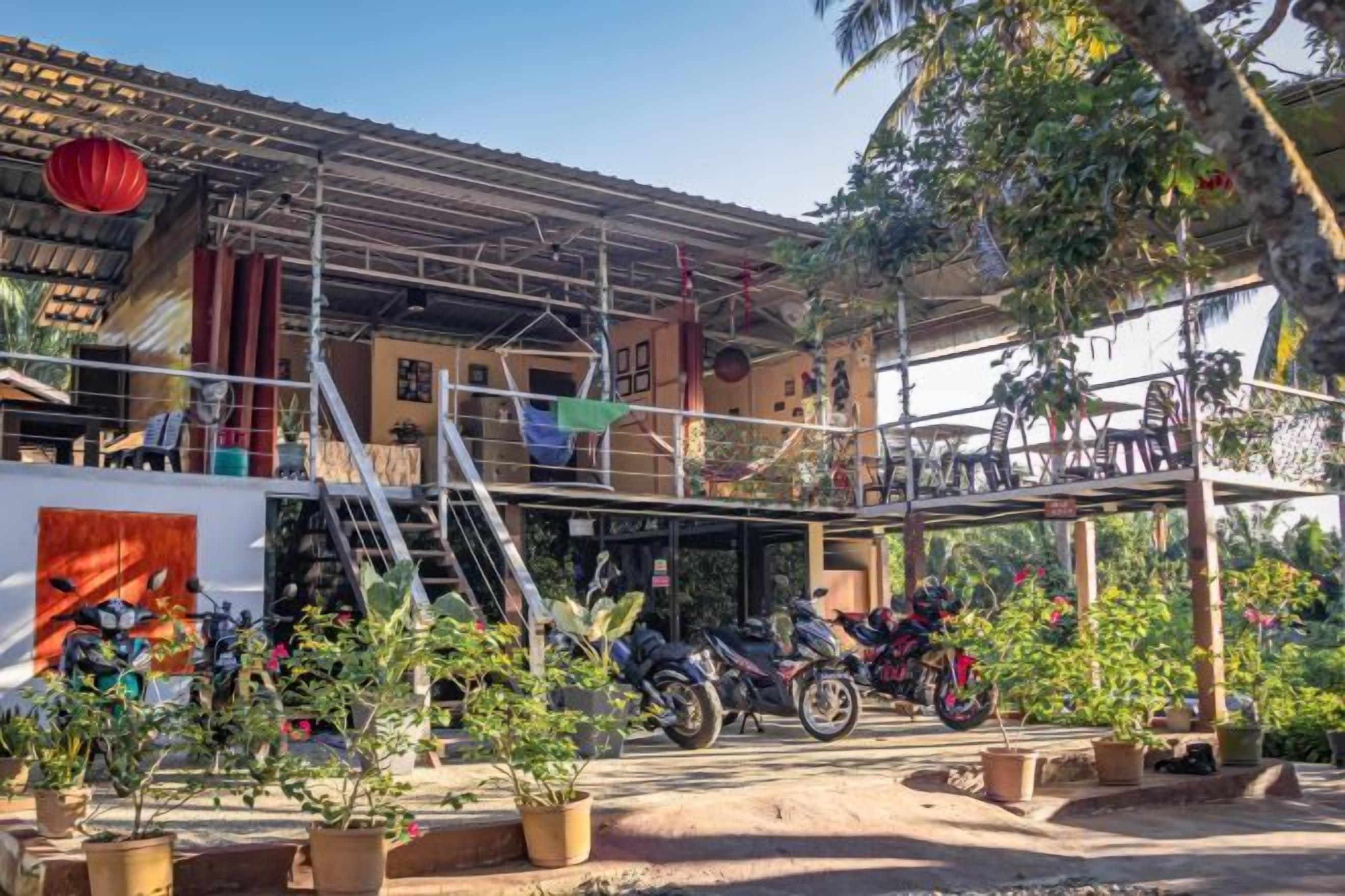 Un bâtiment doté d’un espace extérieur abrité, de plantes en pot et d’une moto.