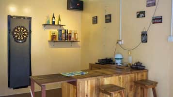 Un espace bar avec un jeu de fléchettes, des étagères remplies de bouteilles et un comptoir en bois.