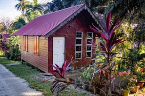 Una pequeña casa de madera con techo rojo, puerta blanca y ventanas.