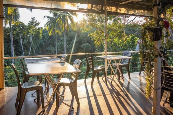 An outdoor dining area with tables and chairs, surrounded by a wooden pergola, overlooking a lush tropical garden. - Timba Garden Semporna Free Town / Jetty Transport (Semporna)