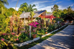 Una casa de techo rojo, rodeada de exuberante follaje y plantas en flor.