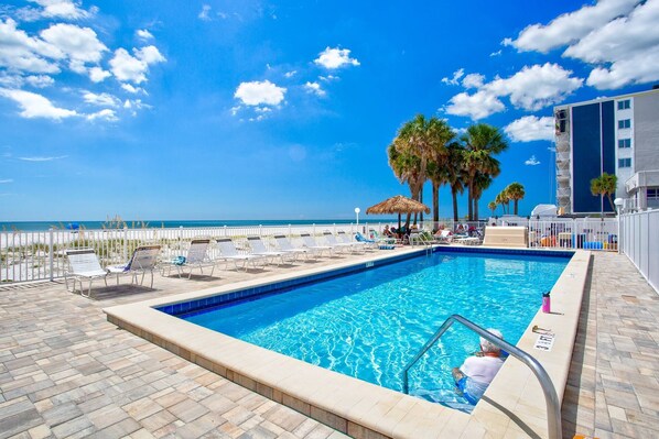 A swimming pool with a view of the beach and palm trees.