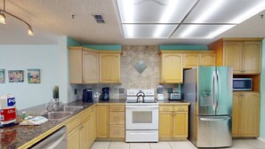 A kitchen with wooden cabinets, a stainless steel refrigerator, a white stove, and a microwave.