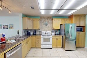 A kitchen with wooden cabinets, a stainless steel refrigerator, a white stove, and a microwave.