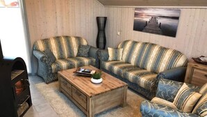 Un salon avec des canapés à rayures, une table basse en bois et un tableau accroché au mur.