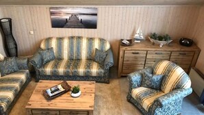 Un salon chaleureux avec des canapés à rayures, une table basse en bois et une vue sur une jetée.