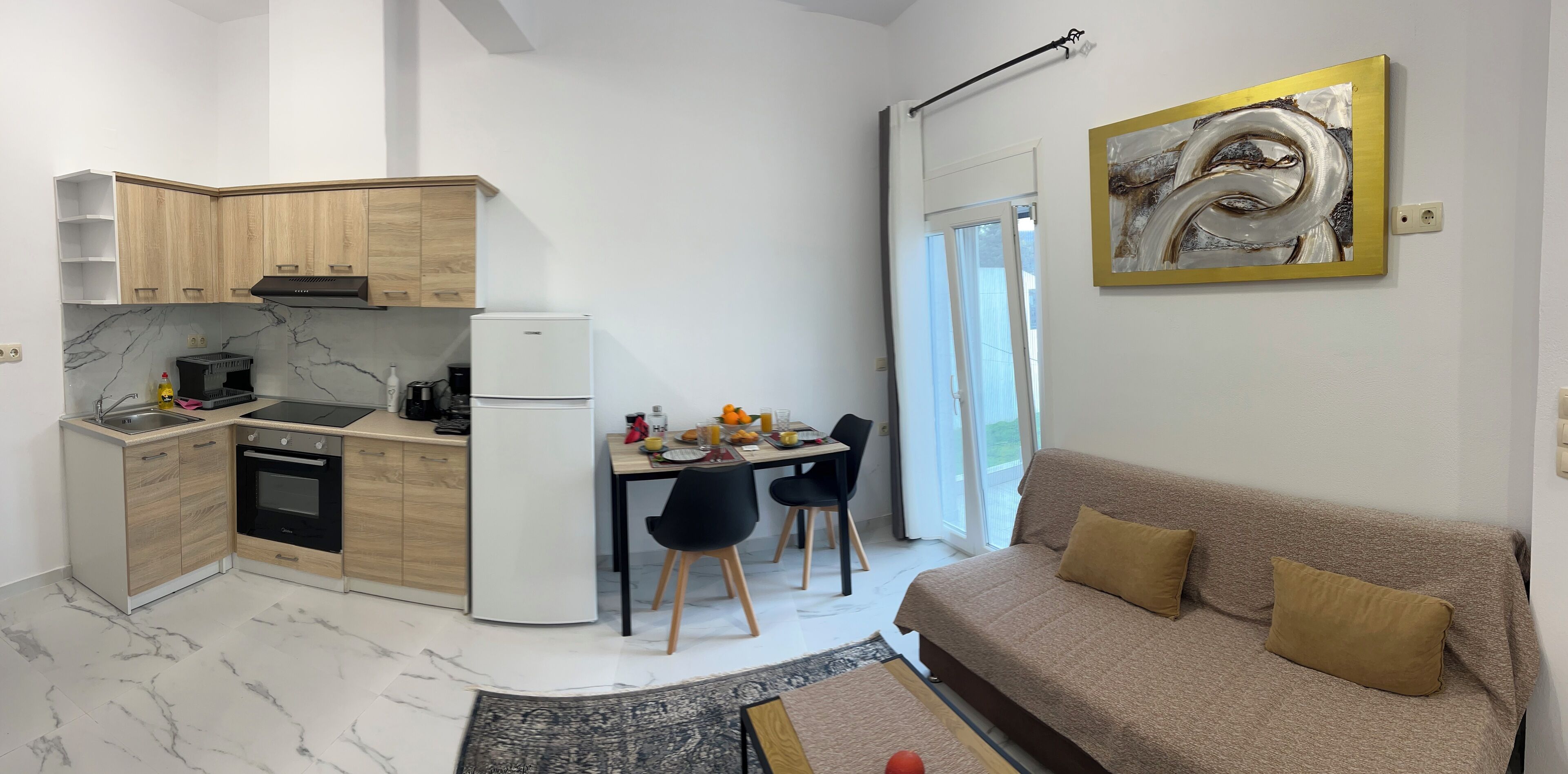 A compact living space with a kitchenette, dining area, and a sofa.