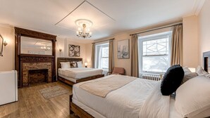 A bedroom with two beds, a fireplace, a chandelier, and large windows. - 10 Double Room (Québec)