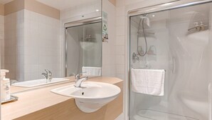 A modern bathroom with two sinks, a glass shower enclosure, and a large mirror. - 10 Double Room (Québec)