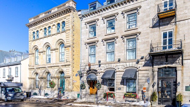 A historic building with multiple stories, large windows, and a prominent entrance with a sign.