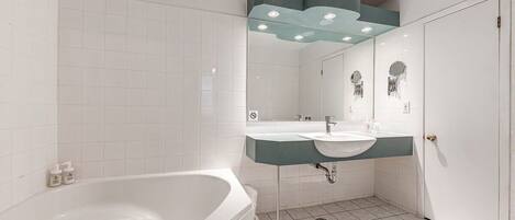 A modern bathroom with a freestanding bathtub, a vanity with a sink, and a mirror with decorative elements.